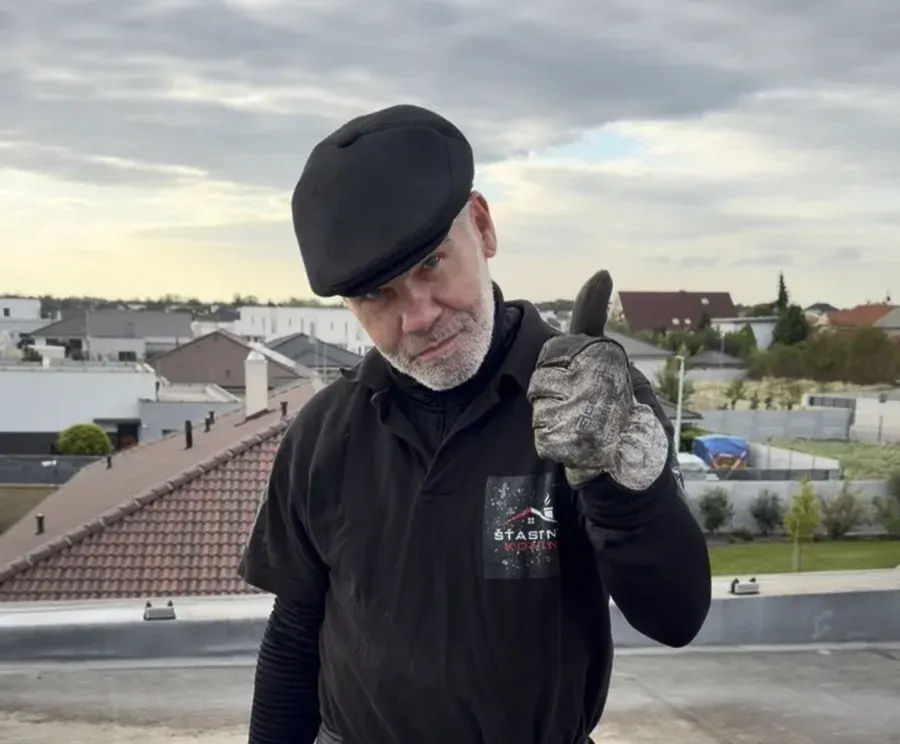 Kominár na streche pri komíne ukazuje palec hore po dokončenej práci